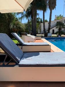 Duas espreguiçadeiras e um guarda-sol junto a uma piscina em B&B A Casa Di Joy em Lecce