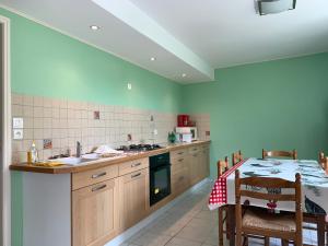 una cucina con pareti verdi, tavolo e bancone di Spacieuse maison dans un parc privée a Vareilles