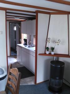 a kitchen with white cabinets and a sink and a trash can at Stacaravanverhuur KR00N chalet FF-5 in Workum