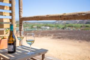 a bottle of wine and two glasses on a table at Hortas do Rio - Casa de Campo in Carrapateira