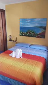 a bedroom with a colorful bed with a painting on the wall at camera azzurra San Vito Lo Capo in San Vito lo Capo