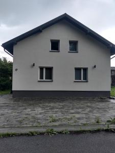 a white house with three windows on the side of it at Park in Rymanów