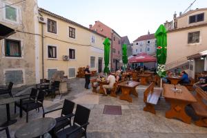 a group of people sitting at tables in a courtyard at Apartment Seka Oldtown in Senj