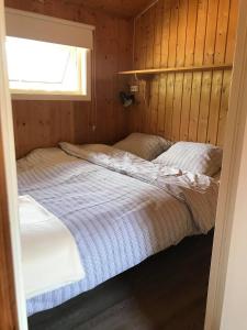 a bedroom with two beds in a wooden wall at Nesheim Hytter & Camping in Bjordal