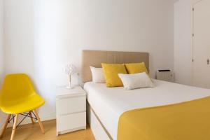 sypialnia z łóżkiem i żółtym krzesłem w obiekcie LUMINOSO APARTAMENTO en el centro de Cádiz w Kadyksie