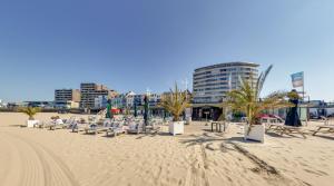 einen Strand mit Stühlen und Palmen und ein Gebäude in der Unterkunft Beachrooms Pier 7 in Vlissingen