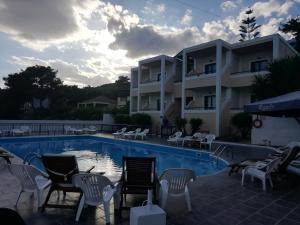 a swimming pool with chairs and a building at Anna Studios in Agia Marina Aegina