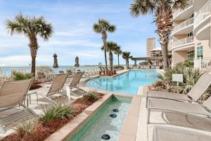 a resort pool with chairs and palm trees and the ocean at Aqua Resort in Panama City Beach