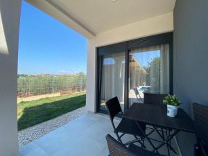 a patio with a table and chairs and a large window at Enjoy Green, APP with swimming pool, garden, pets welcome in Novigrad Istria