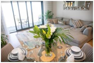 a living room with a glass table with a vase of flowers at 5 Star Fistral View in Newquay