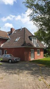 a house with a car parked in front of it at Ferienwohnung Weinberg in Wesselburener Deichhausen