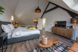 a bedroom with a large bed and a tv at Noorderhaecks Suites & Apartment in 't Horntje