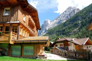 a group of wooden buildings with mountains in the background at Chalet Tobià Apartments in Canazei