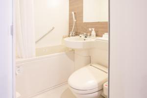 a white bathroom with a toilet and a sink at Kuretake Inn Nagoya Hisayaodori in Nagoya