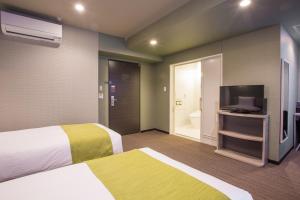 a hotel room with two beds and a flat screen tv at Kuretake Inn Nagoya Hisayaodori in Nagoya