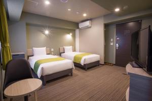 a hotel room with two beds and a flat screen tv at Kuretake Inn Nagoya Hisayaodori in Nagoya