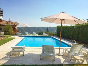 a swimming pool with chairs and an umbrella next to it at Villa Belvedere Liberty in Costermano