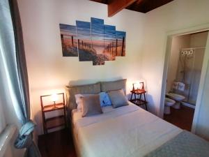 1 dormitorio con 1 cama con 2 lámparas y 2 pinturas en la pared en Casa das Laranjeiras e parque infantil, en Villa Nogueira