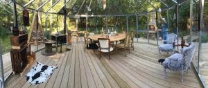 a wooden deck with a table and chairs in a greenhouse at Bäverli Hills in Lidköping