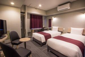 a hotel room with two beds and a flat screen tv at Kuretake Inn Nagoya Hisayaodori in Nagoya