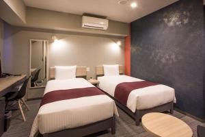 a hotel room with two beds and a desk at Kuretake Inn Nagoya Hisayaodori in Nagoya