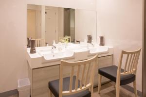 a bathroom with two chairs and a sink and a mirror at Kuretake Inn Nagoya Hisayaodori in Nagoya