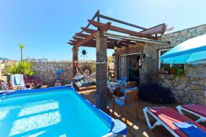 einen Pool mit einer hölzernen Pergola und ein Haus in der Unterkunft Apartamento Yaiza in Nerja