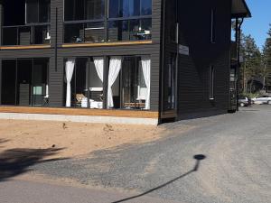 a black building with white curtains in the window at Kalajoen Hiekkasärkät Auringonsäde A1 in Kalajoki +6 photos