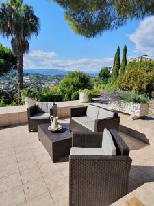a patio with wicker chairs and tables with a view at Haus mit Garten über der Bucht von Cannes in Vallauris