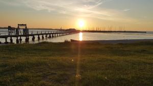 a pier with the sun setting over the water at Haus Moewennest in Gelting