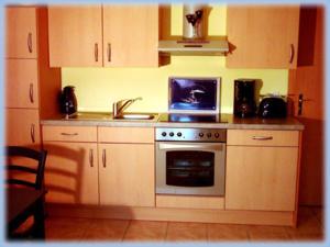 a kitchen with a stove and a sink and a microwave at Haus Moewennest in Gelting