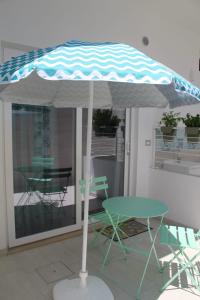 un tavolo e delle sedie sotto un ombrellone in un patio di GIOANTHONY monolocale a Porto Cesareo