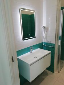 un bagno con un lavandino bianco e uno specchio di GIOANTHONY monolocale a Porto Cesareo