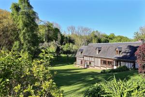 ein altes Haus in einem Hof mit Bäumen und Gras in der Unterkunft Les Fermes de Florence Bien être et nature in Les Champeaux