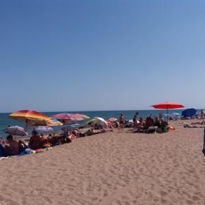 un grupo de personas sentadas en una playa con sombrillas en Caramel' en Illichivsʼk
