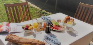 a white table with food and drinks and a book at Fleurs de Cosmos, suite lumineuse climatisée in Albi