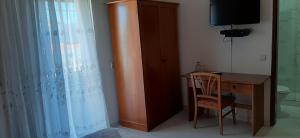 um quarto com uma secretária, uma televisão e um armário de madeira em Bela Alexandra Guest House em Fuzeta