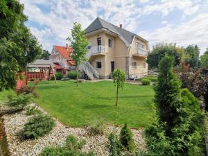 a large house with a yard with a green lawn at Family Garden Apartmanház in Siófok