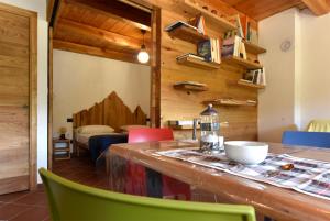 Cette chambre est dotée de murs en bois et d'une table avec des chaises colorées. dans l'établissement ALTESTANZEOSTANA, à Ostana