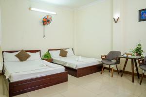 una habitación con dos camas y una mesa y una silla en Aqua Kim Long Hotel, en Ho Chi Minh