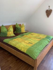 フロイデンシュタットにあるFerienwohnung Frühlingsauの籐製のベッド(緑と黄色の毛布、枕付)