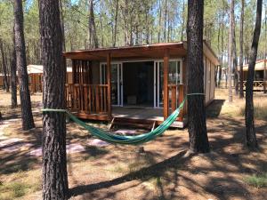 eine Hängematte vor einer Hütte im Wald in der Unterkunft Odeceixe Bungalow-Parque de Campismo Sao Miguel in Odeceixe