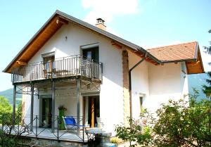a white house with a balcony and a porch at Apartments Leni in Postojna