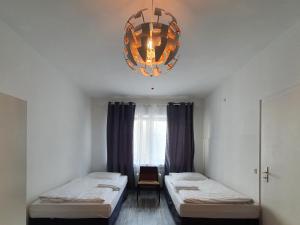 a room with two beds and a chandelier at Aparthouse Graf-Adolf in Düsseldorf