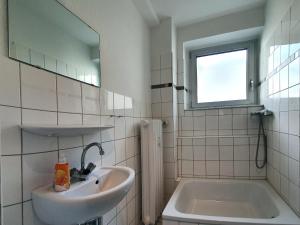 a bathroom with a sink and a tub and a mirror at Aparthouse Graf-Adolf in Düsseldorf