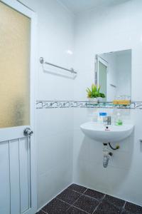ein weißes Badezimmer mit einem Waschbecken und einem Spiegel in der Unterkunft Aqua Kim Long Hotel in Ho-Chi-Minh-Stadt