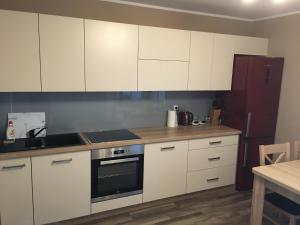 kuchnia z białymi szafkami, lodówką i stołem w obiekcie Apartament Ełk Promenada w mieście Ełk
