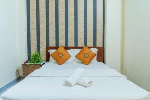 ein Bett mit zwei Kissen und zwei Handtüchern darauf in der Unterkunft Aqua Kim Long Hotel in Ho-Chi-Minh-Stadt