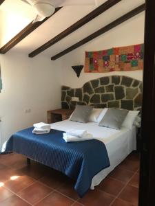 a bedroom with a large bed with a blue blanket at Mayte Dreams Caminito Del Rey in Valle de Abdalagís