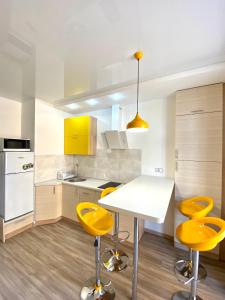 een keuken met een witte tafel en gele krukken bij Grey&Yellow на Коцюбинського in Vinnytsya